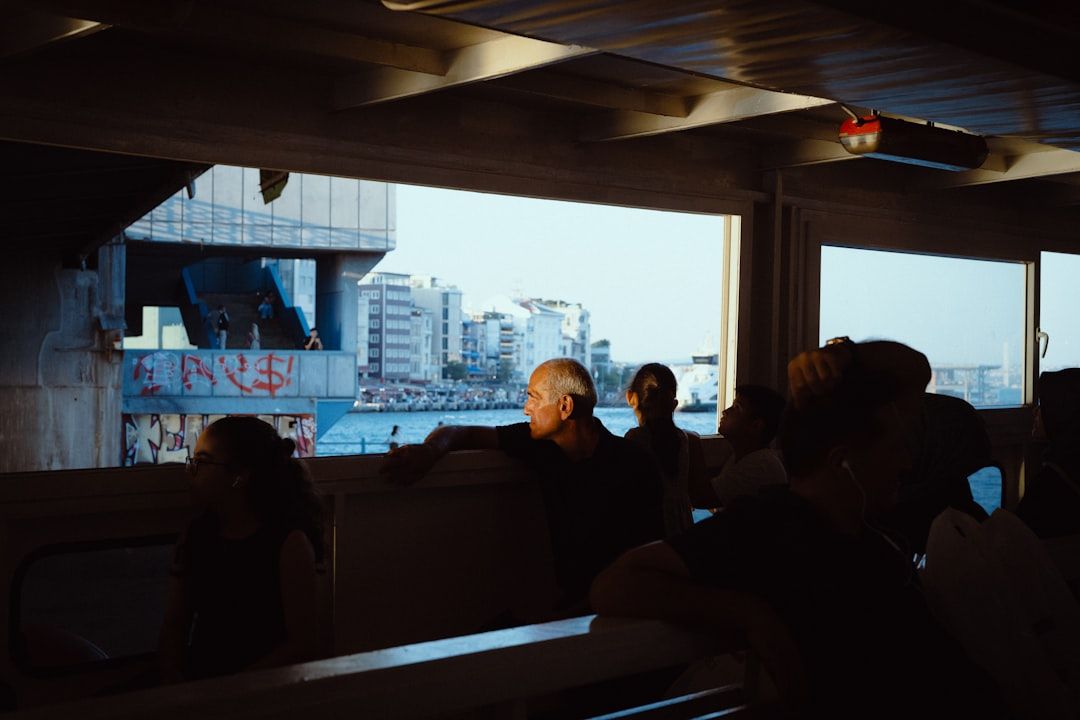 People looking out from a ferry window at a city waterfront with graffiti