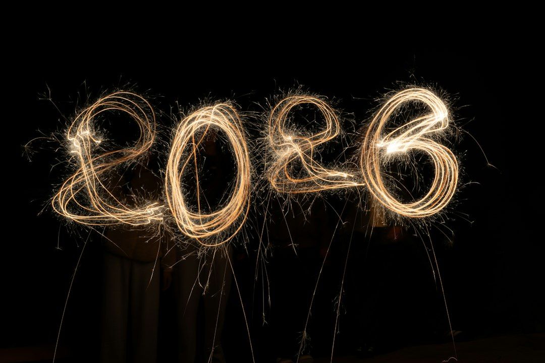 The number 2026 written in glowing golden sparkler light against a dark background