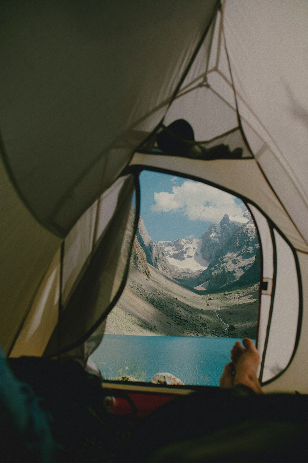 A view from inside a tent looking out at a blue lake and mountains