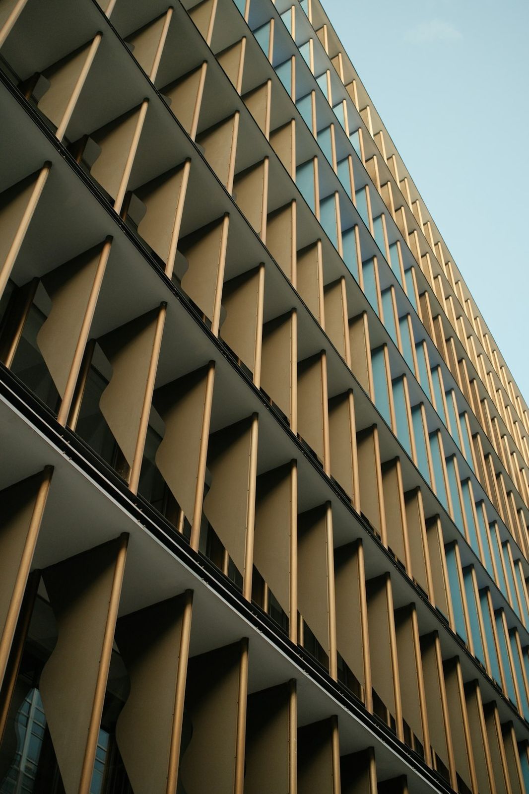 A modern building facade with repeating vertical gold fins and blue glass windows