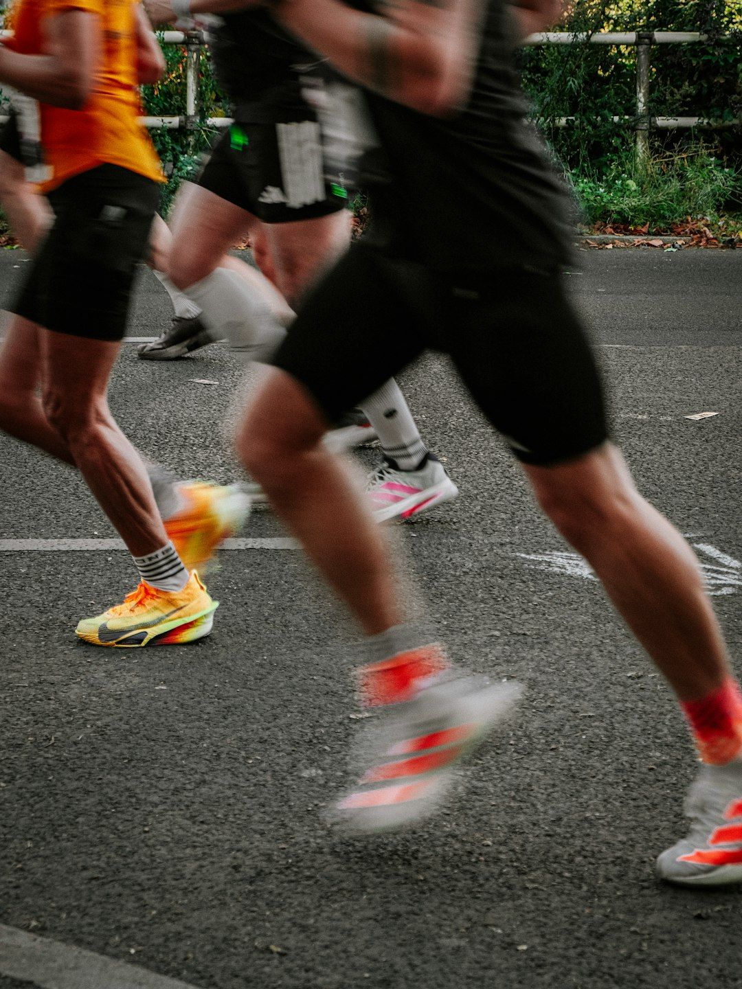 A group of runners in athletic shorts and colorful sneakers racing on asphalt