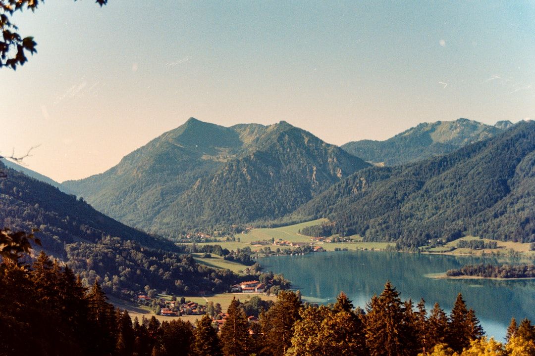 A lake surrounded by green mountains and small villages under a clear sky