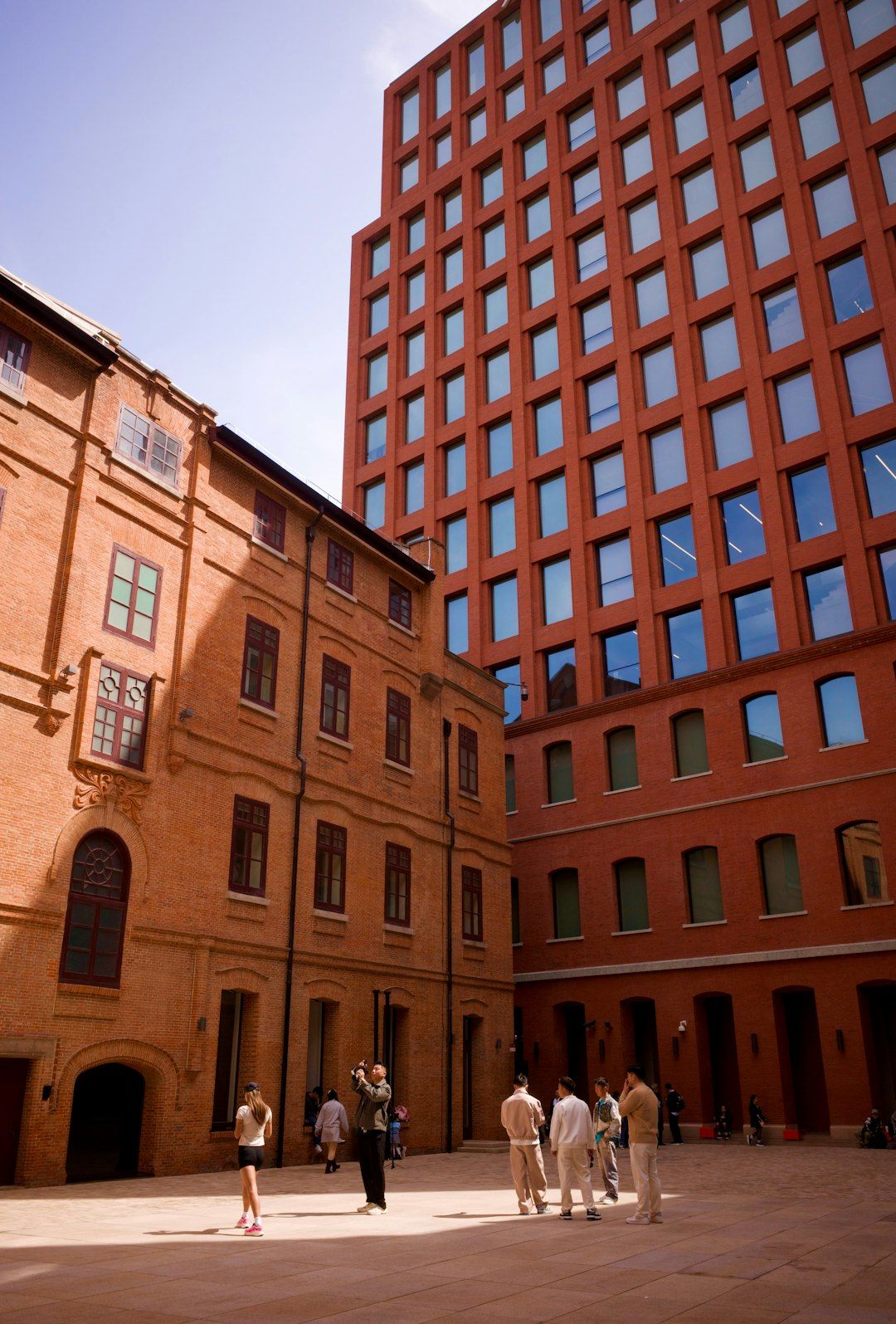 People in a courtyard between old and modern brick buildings